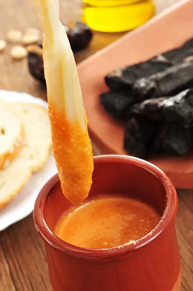 Dipping a calçot in romesco sauce